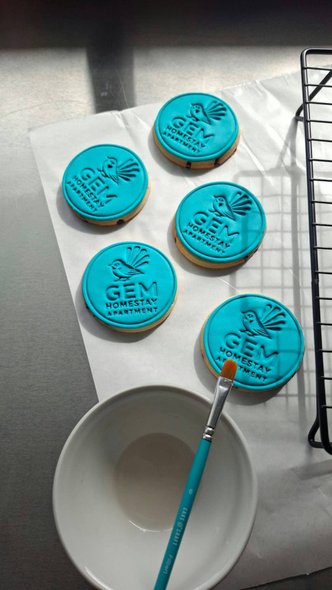 Teal GEM Homestay Apartment logo cookies with a fantail