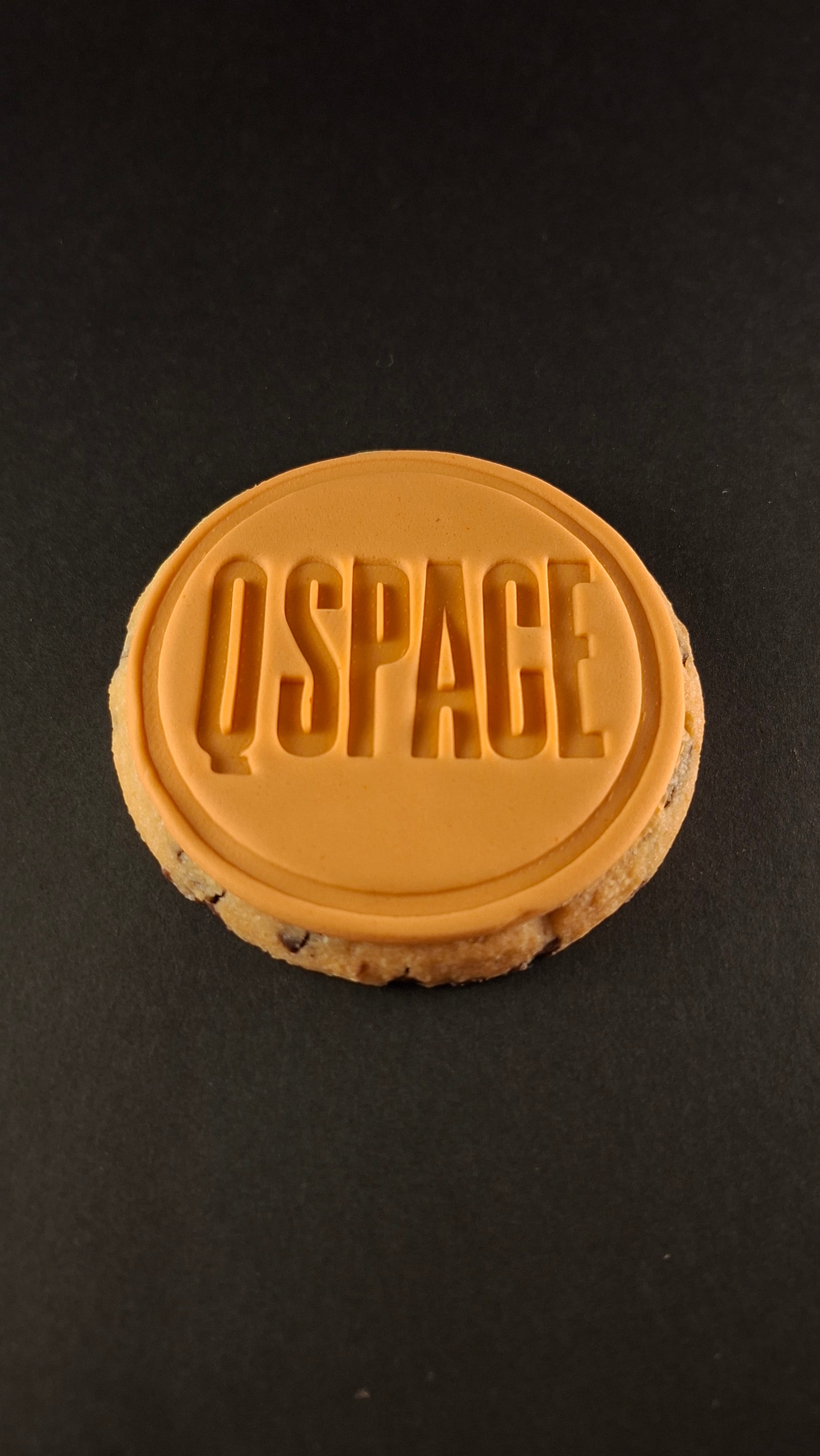 QSpace branded vanilla cookie on black background